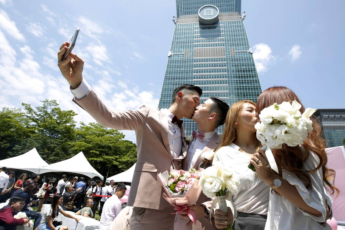 Parejas casadas se besan mientras posan para las fotografías frente al edificio Taipei 101 durante una fiesta a favor del matrimonio entre personas del mismo sexo organizada por el gobierno de la ciudad de Taipei y la Coalición por la Igualdad Matrimonial de Taiwán en Taipei, el viernes 24 de mayo de 2019.