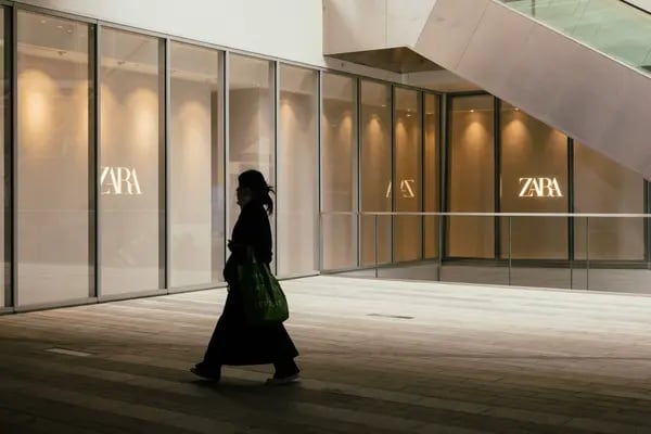Silhueta de uma mulher passando em frente a uma loja da Zara