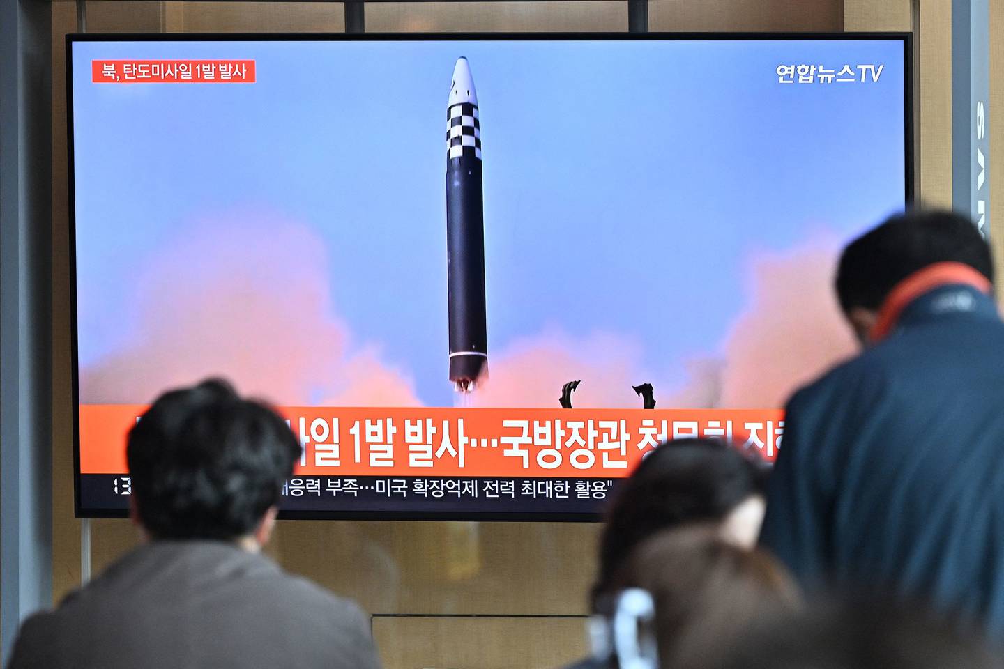Personas miran una pantalla de televisión que muestra un noticiero con imágenes de archivo de una prueba de misiles de Corea del Norte, en una estación de tren en Seúl el 4 de mayo de 2022.