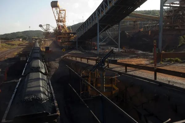 El mineral de hierro triturado se transporta en vagones de ferrocarril, junto a una cinta transportadora, en la mina Brucutu de Vale SA, en Barao de Cocais, Brasil.