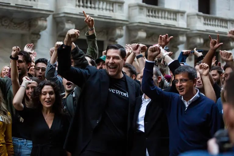 Claure, center, and Sandeep Mathrani, chief executive officer of WeWork, right, cheer with employees in front of the NYSE in October. dfd