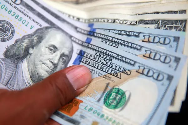 Una persona sostiene varios billetes de dólares. Foto: Bloomberg