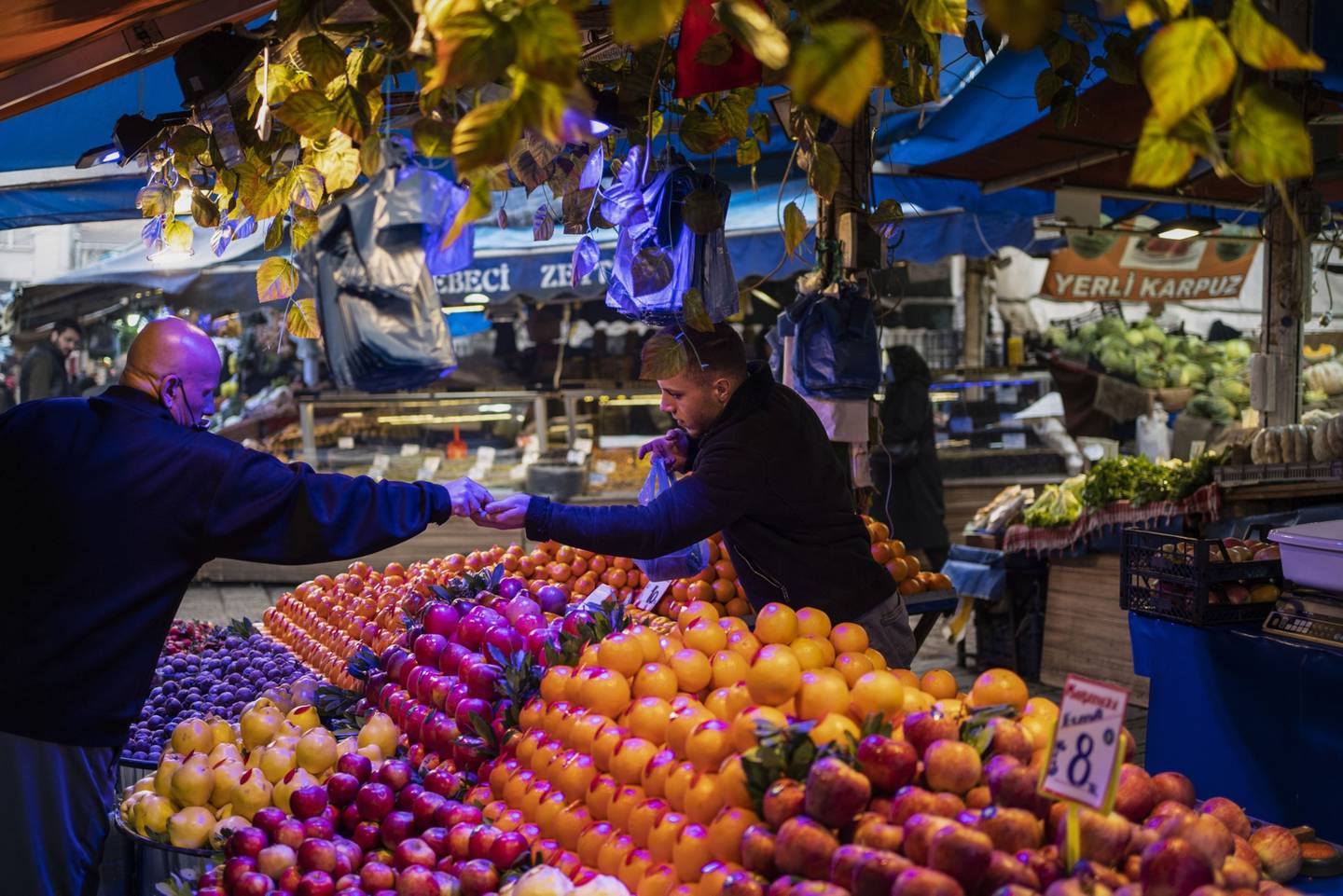 Un vendedor atiende a un cliente en un puesto de productos frescos en un mercado local de Bursa, Turquía.