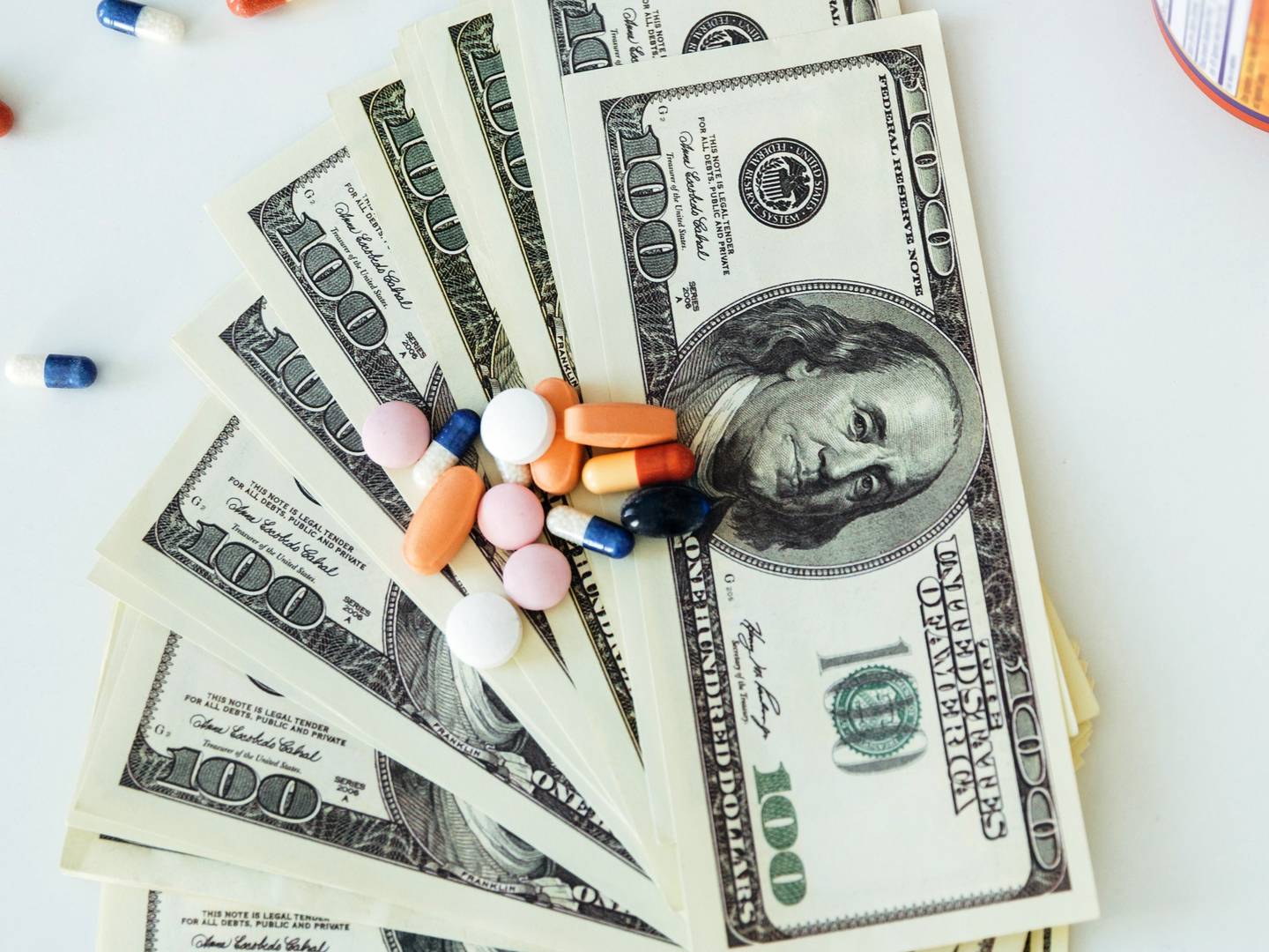 Picture of money with pills and vitamins over white background.