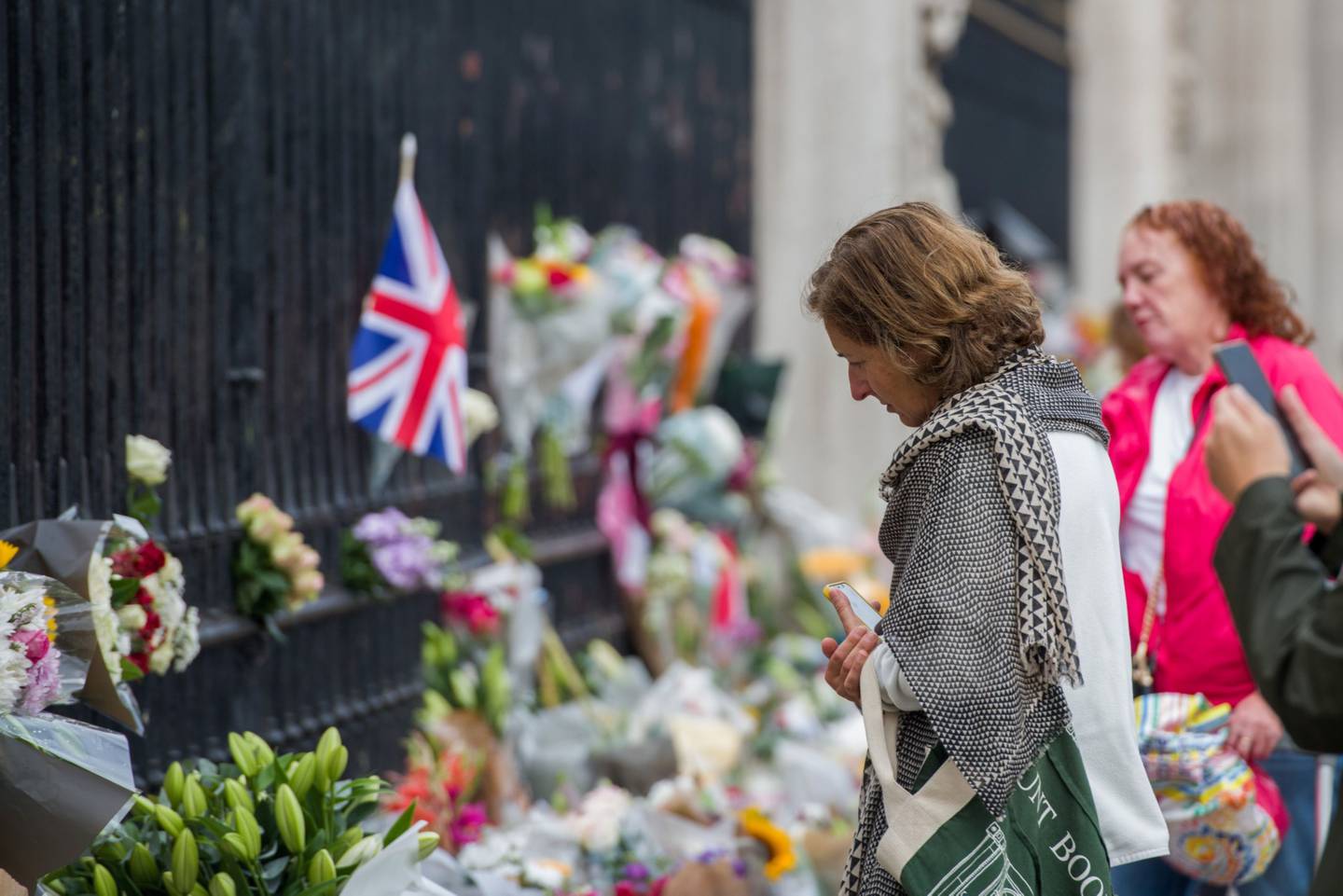 A well-wisher looks at floral tributes at the gates of Buckingham Palace on the first day of public mourning following the death of Queen Elizabeth II, in central London, UK, on Friday, Sept. 9, 2022.