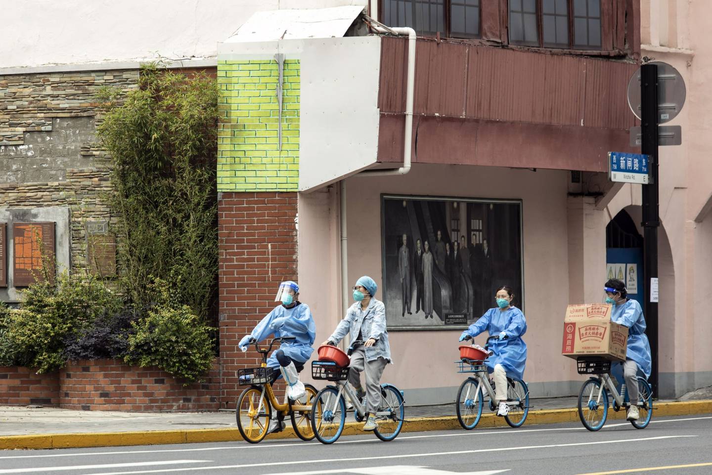 Trabajadores con equipamiento protector andan en bicicleta en Shanghái