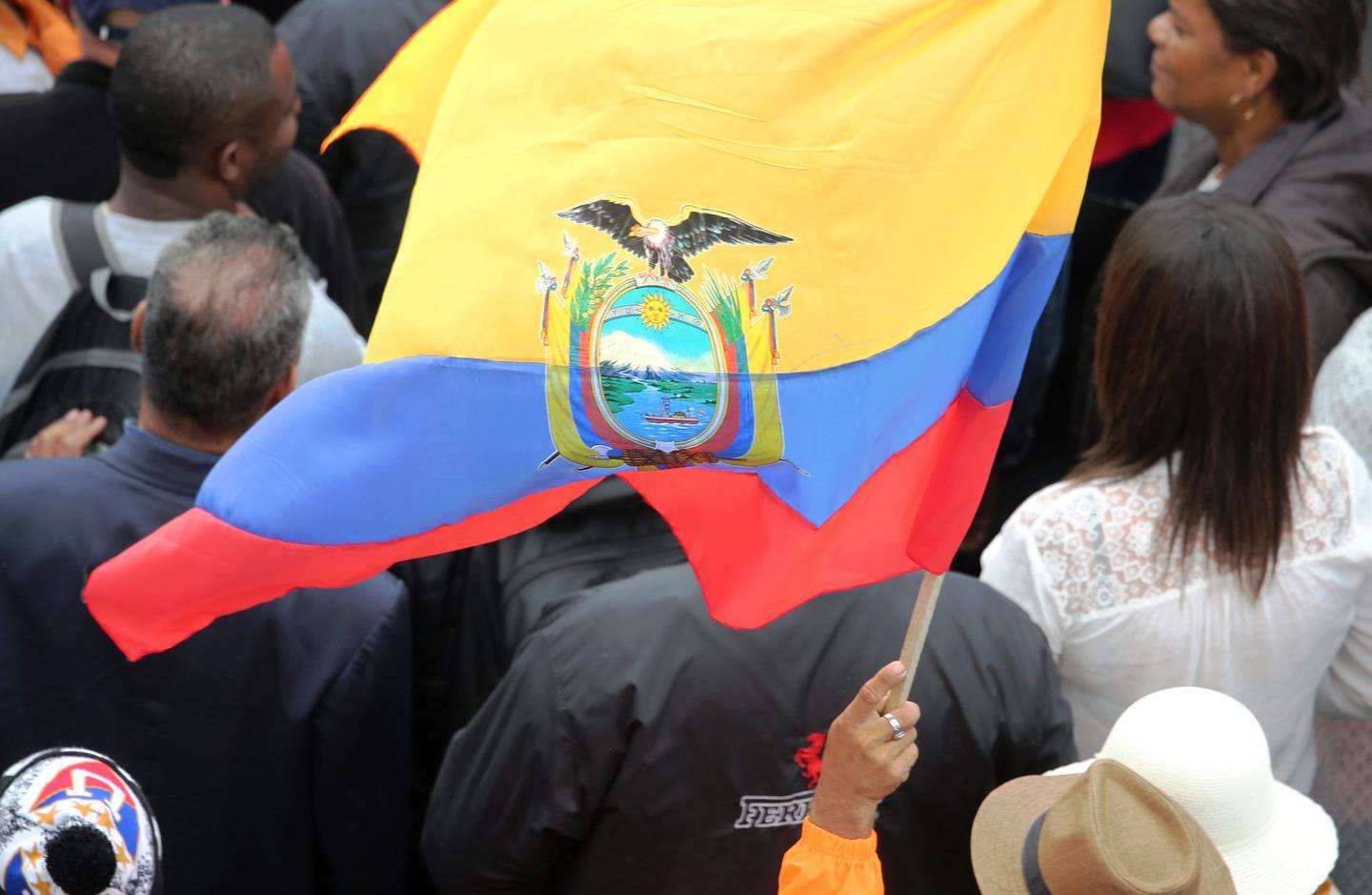 Citizens carry an Ecuadorian flag.