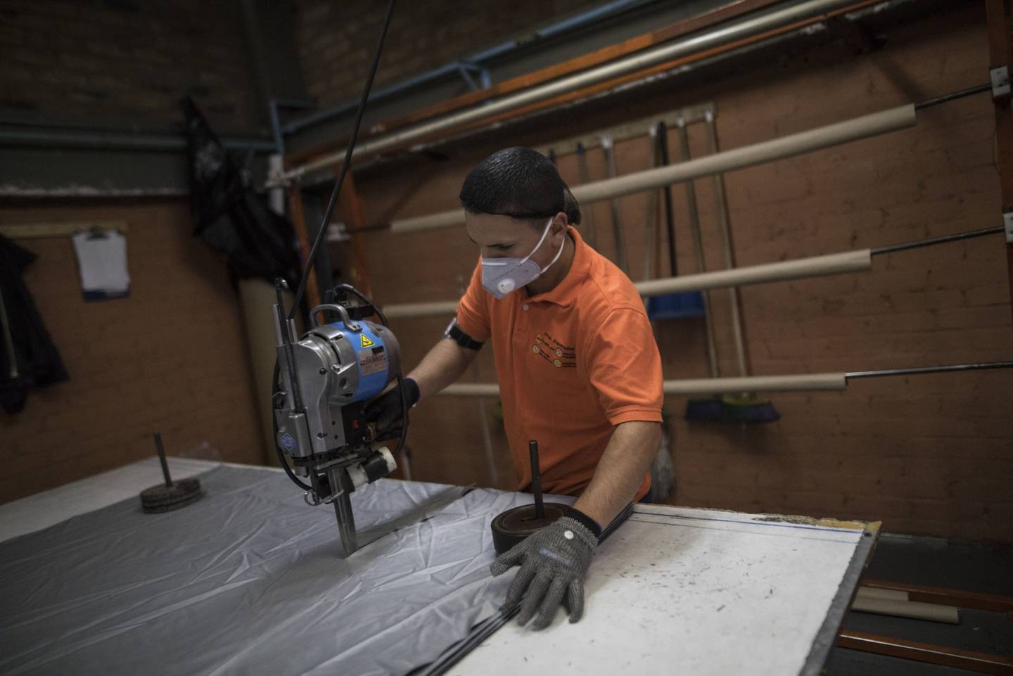 Un empleado que usa una máscara protectora corta telas en una fábrica de Espumados SA en Soacha, Colombia, el lunes 27 de abril de 2020.