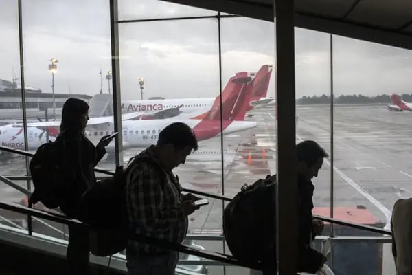 Los viajeros se mueven por una escalera mecánica frente a los aviones de pasajeros de Avianca Holdings SA sentados en la pista en el Aeropuerto Internacional El Dorado (BOG) en Bogotá, Colombia, el martes 31 de octubre de 2017.