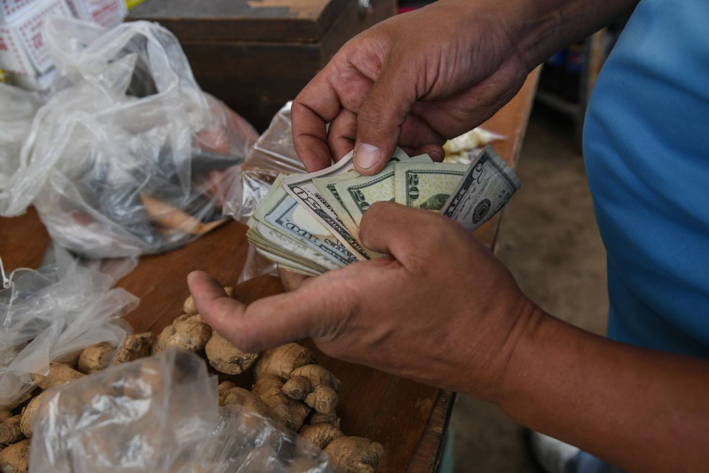 A vendor counts U.S. dollars at a market in Caracas, Venezuela, on Monday, Oct. 4, 2021. Venezuela is launching a new version of the bolivar in the latest attempt to salvage a currency so beaten down by years of hyperinflation that residents have adopted the U.S. dollar.