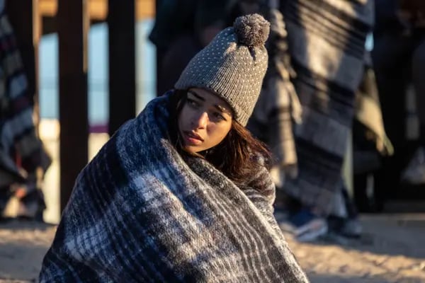 A Colombian immigrant bundles up against the cold after spending the night camped alongside the U.S.-Mexico border fence on Dec. 22, 2022 in El Paso, Texas.