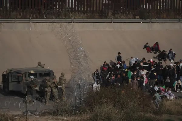 Migrants are apprehended by the US National Guard after crossing the US and Mexico border through the Rio Grande into El Paso, Texas, seen from Ciudad Juarez, Chihuahua state, Mexico, on Tuesday, Dec. 20, 2022. Chief Justice John Roberts temporarily blocked the scheduled ending of pandemic-era border restrictions while the US Supreme Court considers a bid by Republican state officials to keep the rules in place during a legal fight. Photographer: Eric Thayer/Bloomberg