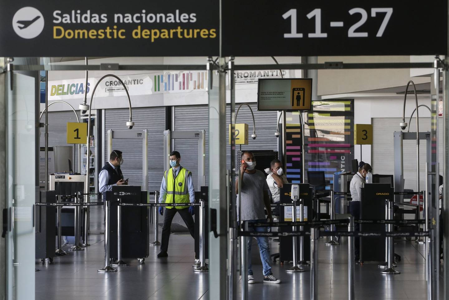 Funcionarios de seguridad con máscaras protectoras se paran frente a un puesto de control de seguridad en el Aeropuerto Internacional El Dorado en Bogotá, Colombia, el domingo 22 de marzo de 2020.
