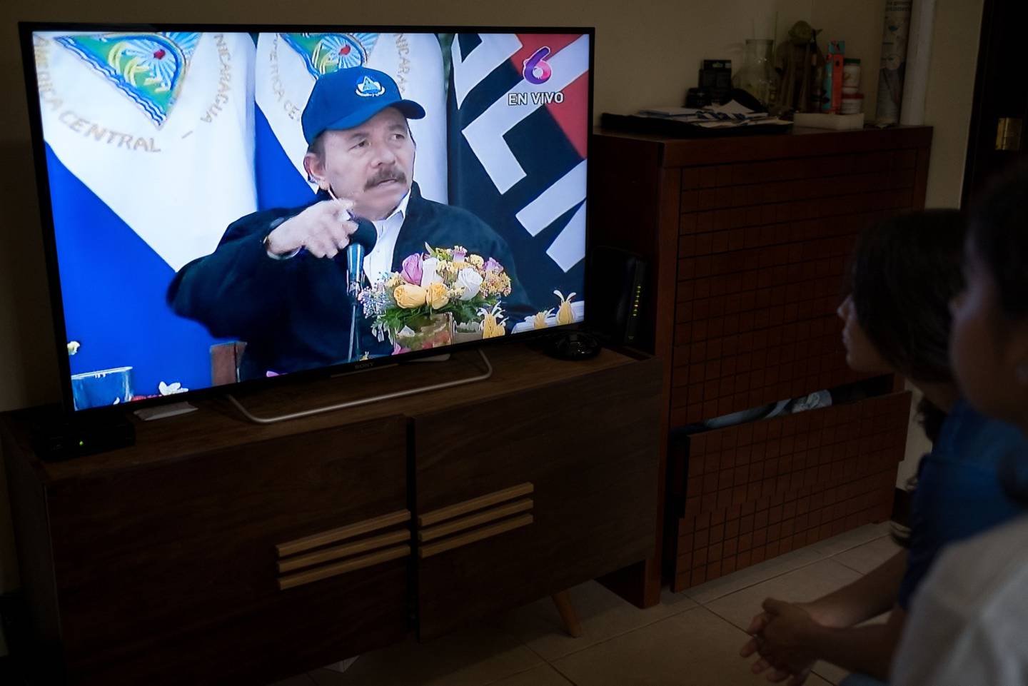 People listen as Daniel Ortega, Nicaragua's president, is shown on a screen during a televised national address in this arranged photograph in Managua, Nicaragua, on Wednesday, April 15, 2020. Ortega defended the nation's relatively relaxed measures for confronting the coronavirus pandemic, in his first public appearance in more than a month. Photographer: Carlos Herrera/Bloomberg