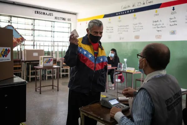 Un votante muestra una identificación antes de emitir su voto en una mesa de votación durante las elecciones regionales en Caracas, Venezuela, el domingo 21 de noviembre de 2021.