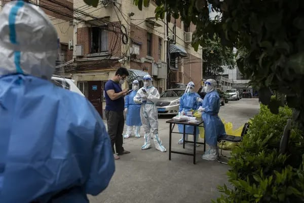 A team of health workers and volunteers in personal protective equipment (PPE) as a resident arrives at a Covid-19 testing station at a neighbourhood where a suspected flare up in cases occurred in Shanghai, China, on Monday, May 9, 2022. The ramping up of restrictions comes even as the city reported its fewest cases in more than six weeks, with 3,947 new infections on Sunday, down slightly from 3,975 on Saturday. Photographer: Qilai Shen/Bloomberg