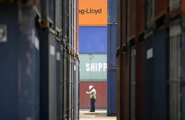 Un trabajador en medio de containers en un puerto