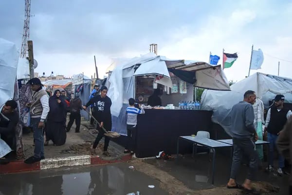 Un hombre palestino remueve tierra para construir un camino a través de los charcos de lluvia en un campamento provisional, gestionado por la Agencia de Obras Públicas y Socorro de las Naciones Unidas (UNWRA), en Khan Younis, Gaza, el domingo 19 de noviembre de 2023.