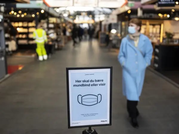 Un cartel pide a los visitantes que lleven mascarillas en el mercado de alimentos de Torvehallerne en Copenhague, Dinamarca, el lunes 17 de enero de 2022.