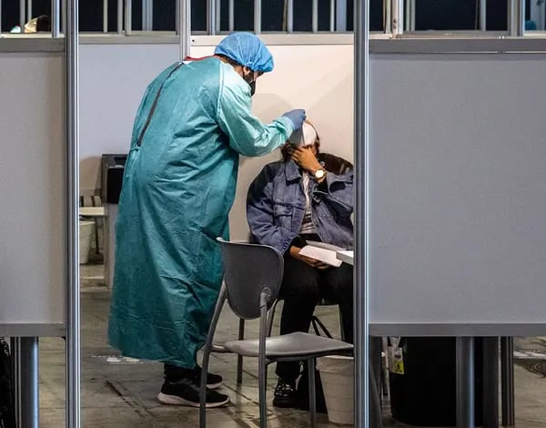 Un trabajador sanitario con equipo de protección personal (EPP) administra una prueba de hisopo a un visitante en la zona de pruebas de Covid-19 en el recinto de Fira de Barcelona antes del MWC Barcelona, el 27 de junio de 2021.