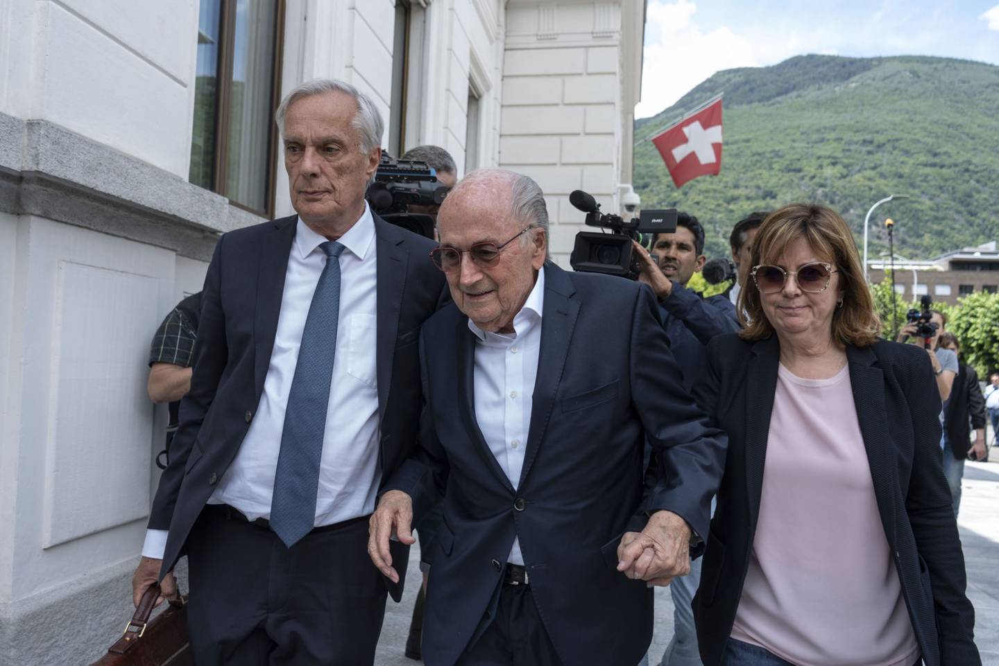 Sepp Blatter, ex-presidente da FIFA, ao centro, na saída de audiência no Tribunal Penal Federal Suíço em Bellinzona, na Suíça, nesta quarta (8)