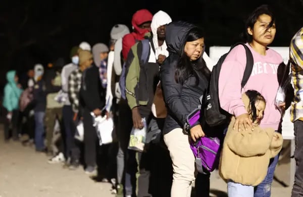 Inmigrantes que solicitan asilo en Estados Unidos hacen cola para ser procesados por agentes de la Patrulla Fronteriza estadounidense a primera hora de la mañana, tras cruzar a Arizona desde México, el 10 de mayo de 2023, en Yuma, Arizona.