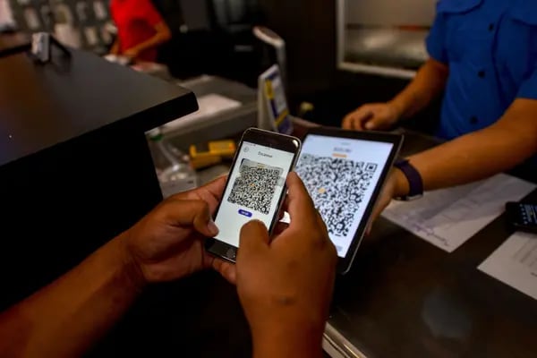 Un cliente paga con la billetera gubernamental Chivo Wallet, en un taller de reparación de teléfonos celulares en San Salvador.