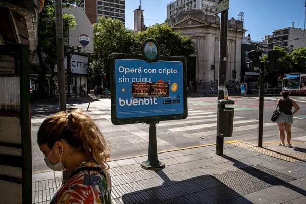 Pedestrians wait for crossing on Cabildo Avenue in front of an advertisement for the Buenbit cryptocurrency exchange in Buenos Aires, Argentina, on Thursday, March 3, 2022. Sports stadiums, buses and highway billboards across Argentina are plastered with adverts for cryptocurrency exchanges, as the nation's economic instability fuels one of the world's biggest booms in digital money.