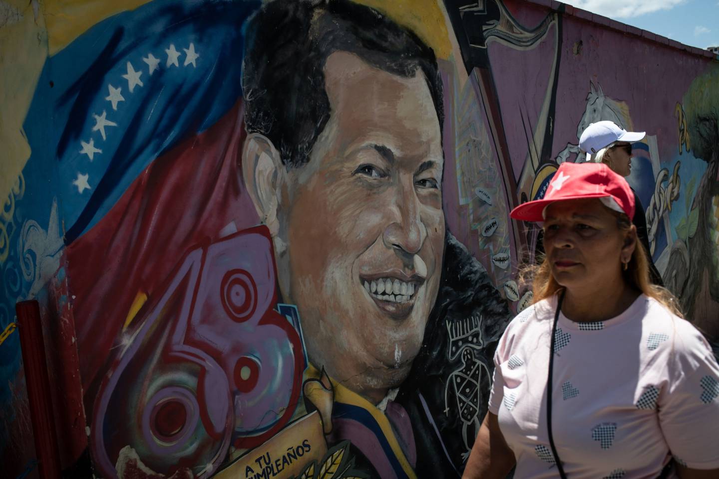 Un manifestante pasa frente a un mural del difunto presidente venezolano Hugo Chávez en el décimo aniversario de su muerte frente al Cuartel de la Montaña 4F en el barrio 23 de Enero de Caracas, Venezuela, el domingo 5 de marzo de 2023.