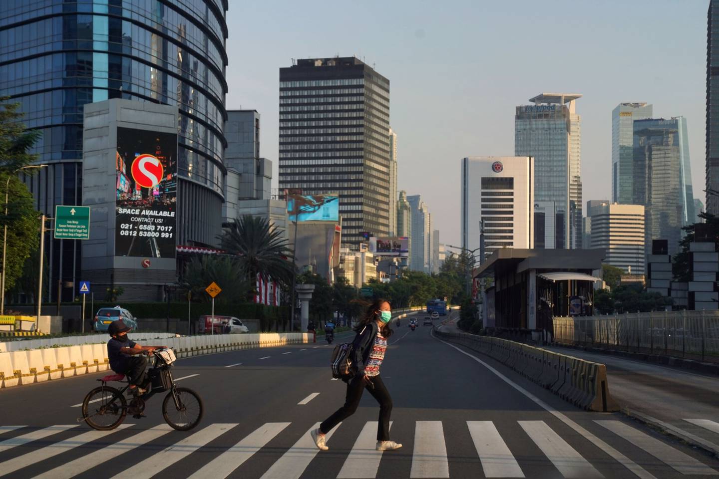Un peatón y un ciclista cruzan una calle casi vacía en el distrito central de negocios en Yakarta, Indonesia, el miércoles 28 de julio de 2021. Indonesia está acelerando la vacunación para alcanzar la inmunidad de grupo, ya que la variante delta del coronavirus, altamente infecciosa, sigue arrasando el país. Fotógrafo: Dimas Ardian/Bloomberg