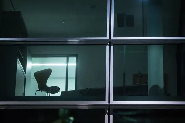 Una silla vacía en una ventana iluminada de un edificio de oficinas en Alemania.