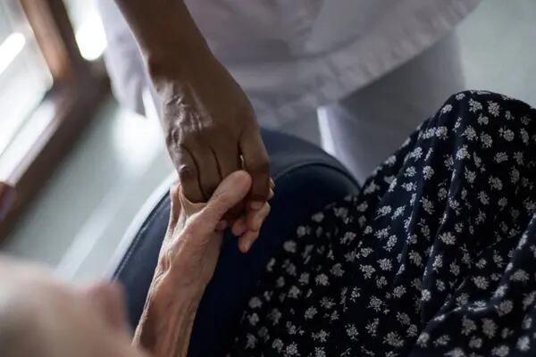 Enfermera cogiendo de la mano a un paciente anciano. Fotógrafo: Fred Dufour