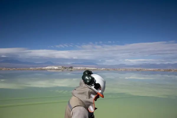 A visitor walks past a brine lake at a Sociedad Química y Minera de Chile (SQM) lithium mine on the Atacama salt flat in the Atacama Desert, Chile.