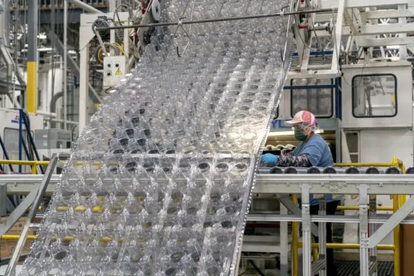 Vasos fabricados con plásticos reciclados se mueven a lo largo de una cinta transportadora.