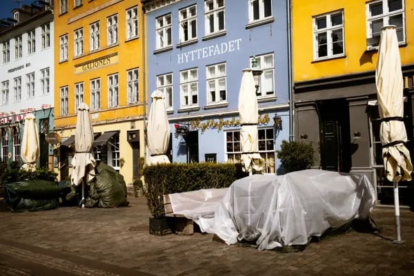 Mesas de las terrazas están cubiertas al exterior de los restaurantes cerrados, en el popular lugar turístico del puerto de Nyhavn en Copenhague, Dinamarca, el miércoles 15 de abril de 2020.