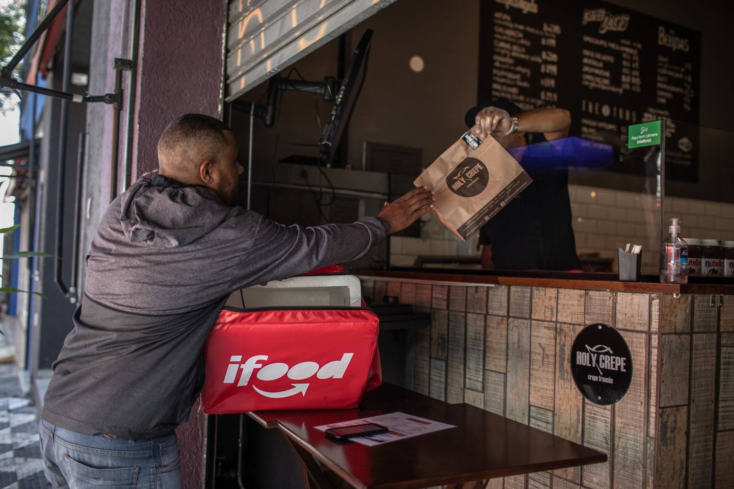 A worker picks up food from a restaurant to make an iFood app delivery in Sao Paulo, Brazil, on Wednesday, April 1, 2020.
