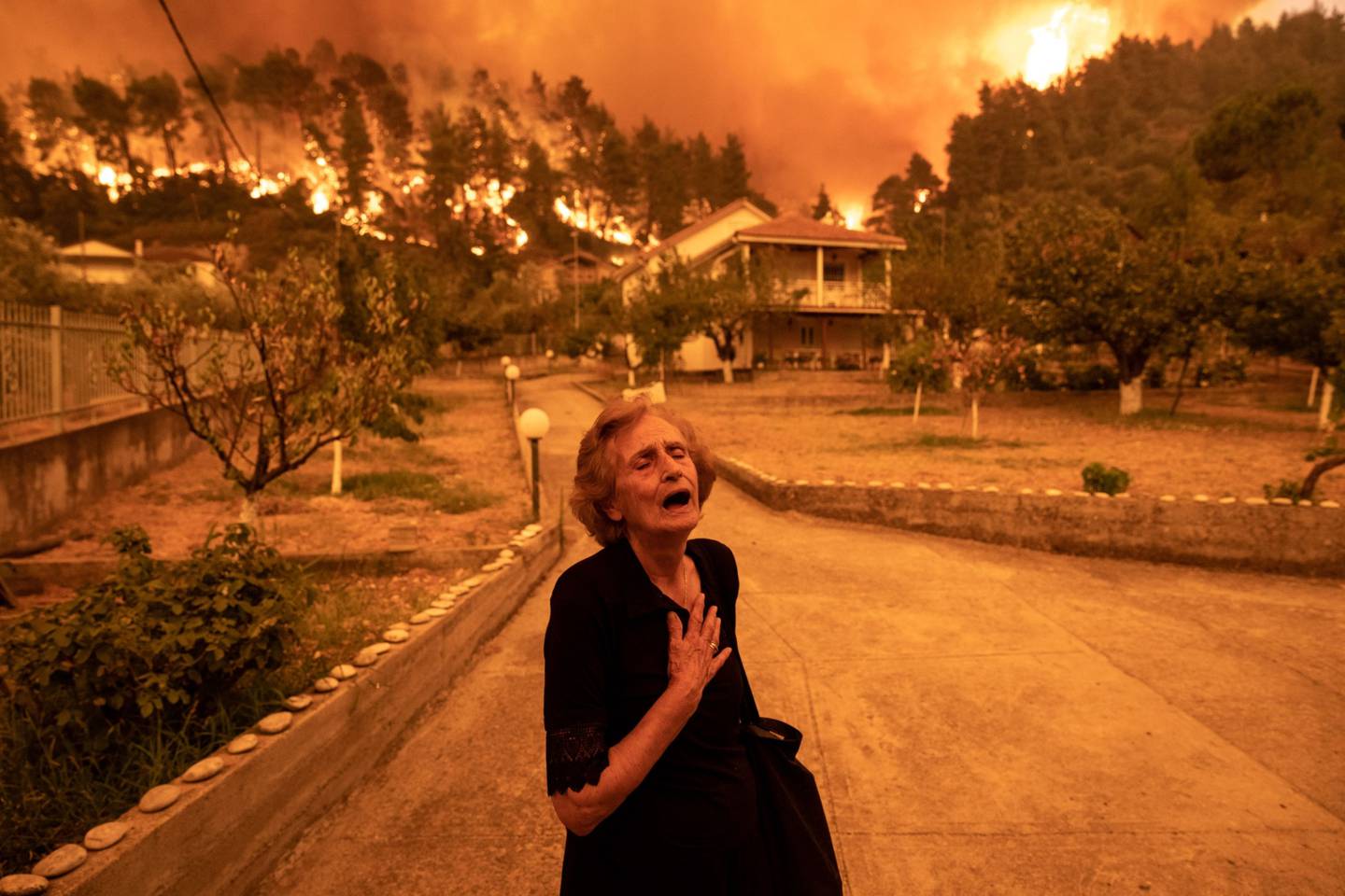 Una residente evacúa una isla griega afectada por incendios