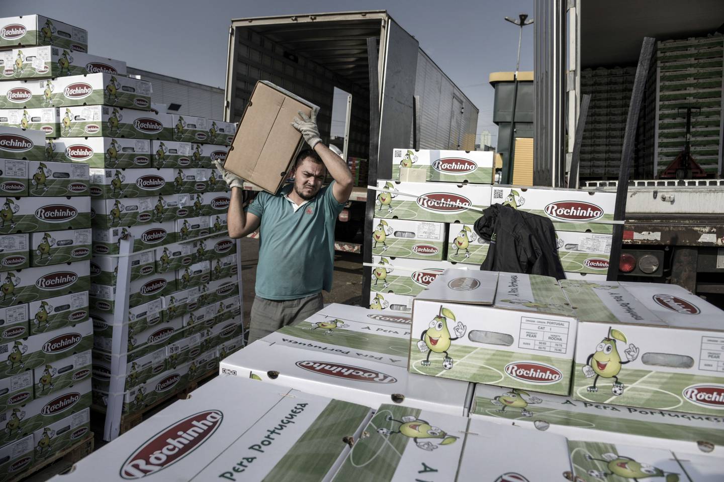 Un trabajador lleva una caja de peras en un centro de distribución en Brasil