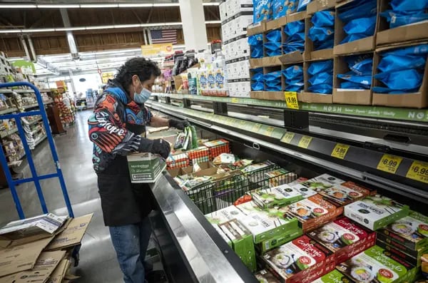 Un trabajador coloca productos en una tienda de comestibles, en San Francisco.