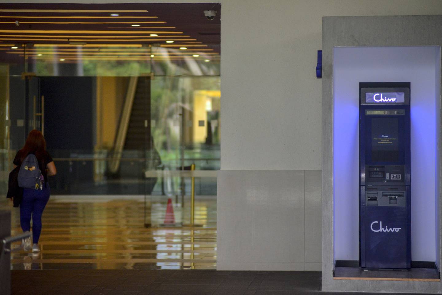 A shopper walks past a Chivo Bitcoin automated teller machine (ATM) booth at the Multiplaza Mall in San Salvador.dfd