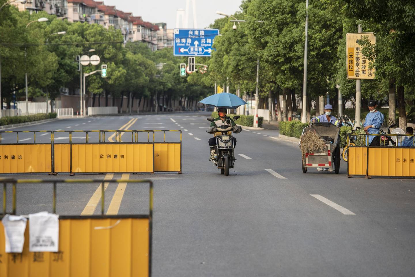 Un motociclista pasa frente a un control sanitario de seguridad en Shanghái