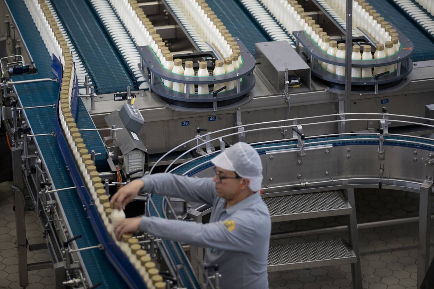 An employee monitors Becel squeezy bottle margarine as it passes along the production line inside the Unilever NV factory in Rotterdam, Netherlands