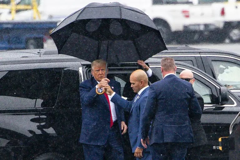 El expresidente estadounidense Donald Trump, a la izquierda, recibe un paraguas de manos de Walt Nauta, ayudante personal del expresidente estadounidense Donald Trump, antes de partir en su avión privado en el Aeropuerto Nacional Ronald Reagan (DCA) en Arlington, Virginia, Estados Unidos, el jueves 3 de agosto de 2023.dfd