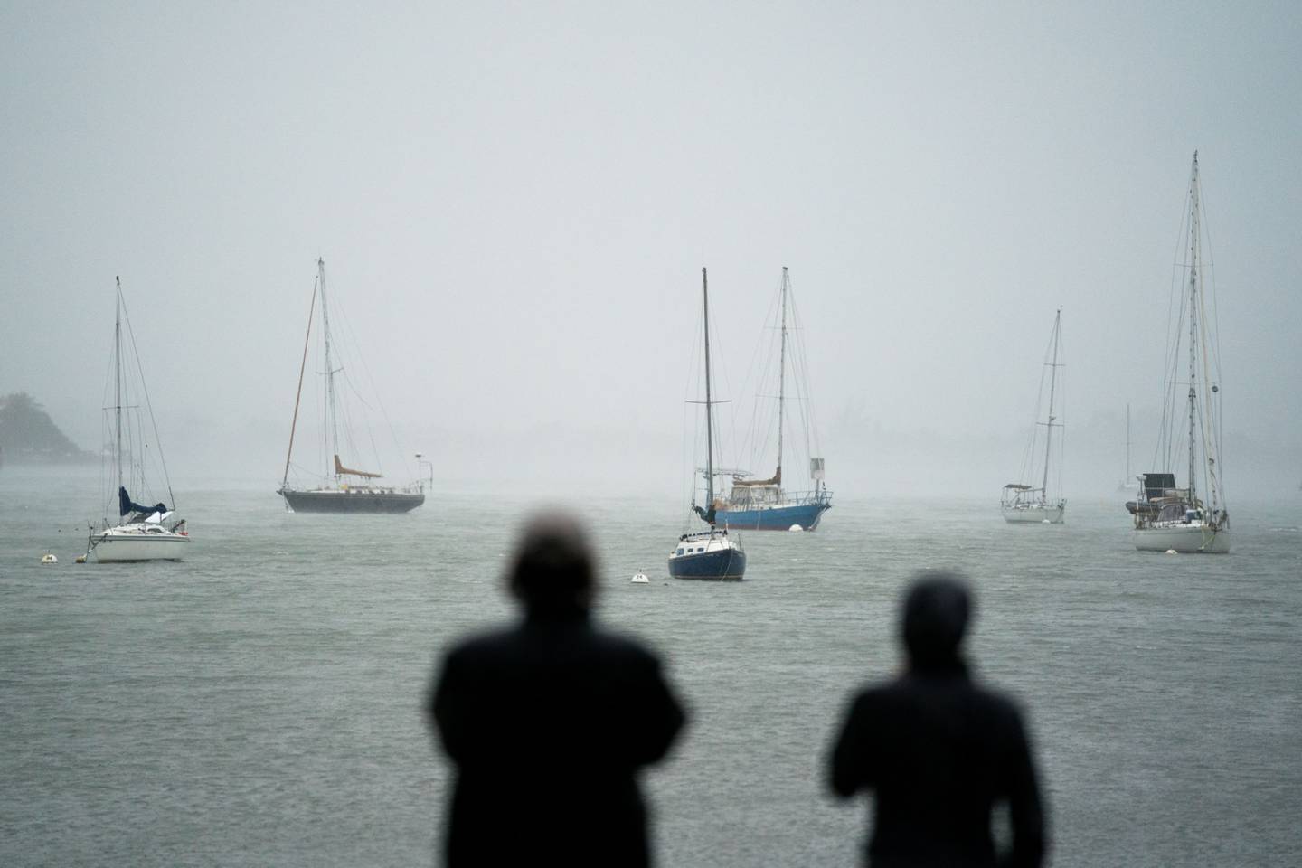 La gente observa los veleros en la bahía de Sarasota mientras el huracán Ian se acerca el 28 de septiembre de 2022 en Sarasota, Florida.