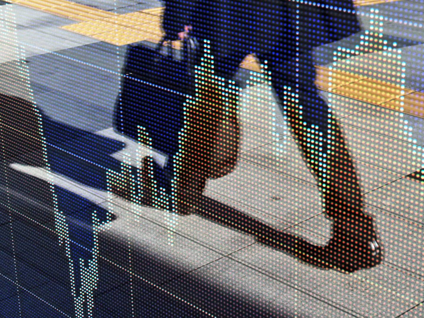 Un hombre de negocios se refleja en un tablero electrónico fuera de una firma de valores en Tokio, Japón.
