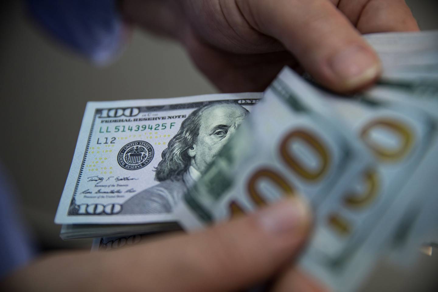 Un hombre cuenta un fajo de billetes de cien dólares estadounidenses en Turquía.