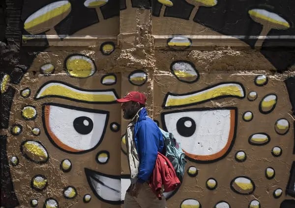 Un hombre camina frente a un grafiti sobre el Covid-19 en Bogotá.