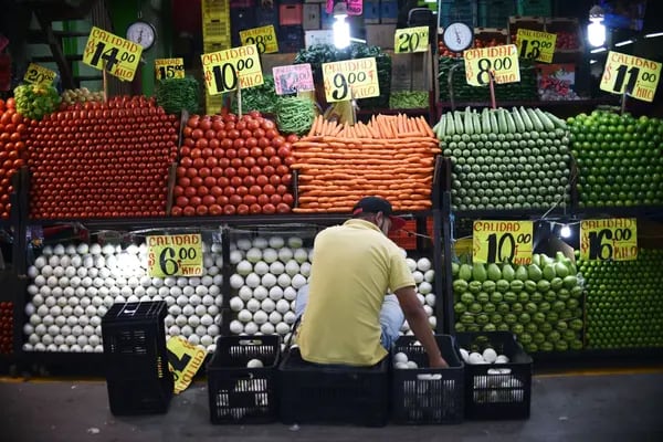 Uma pessoa organiza os vegetais à venda em um mercado