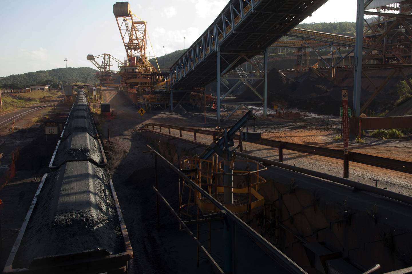 El mineral de hierro triturado se transporta en vagones de ferrocarril, junto a una cinta transportadora, en la mina Brucutu de Vale SA, en Barao de Cocais, Brasil.