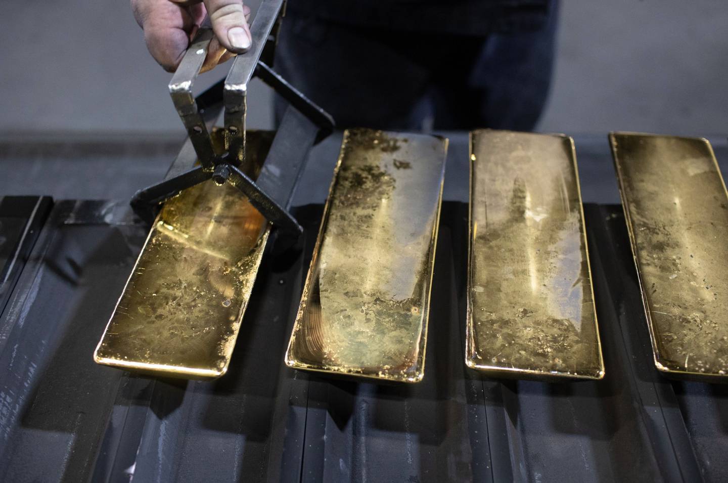 Un trabajador retira lingotes de oro de 12 kilogramos enfriados de sus moldes en la fundición.